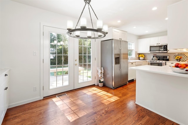 15 Le Britton St, Locust Valley, NY 11560 - kitchen with stainless steel appliances, light countertops, a chandelier, white cabinetry, and backsplash
