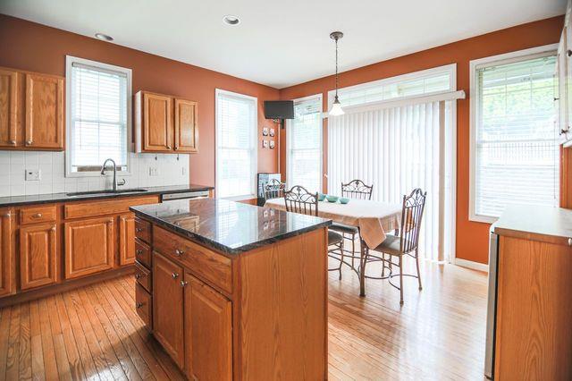 97 Reunion Rd, White Plains, NY 10603 - kitchen with light wood-style flooring, brown cabinets, decorative backsplash, a kitchen island, and recessed lighting