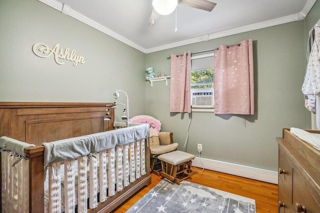 30 Lincoln Ave, Port Jefferson Station, NY 11776 - bedroom featuring a baseboard radiator, ornamental molding, wood finished floors, a crib, and a ceiling fan