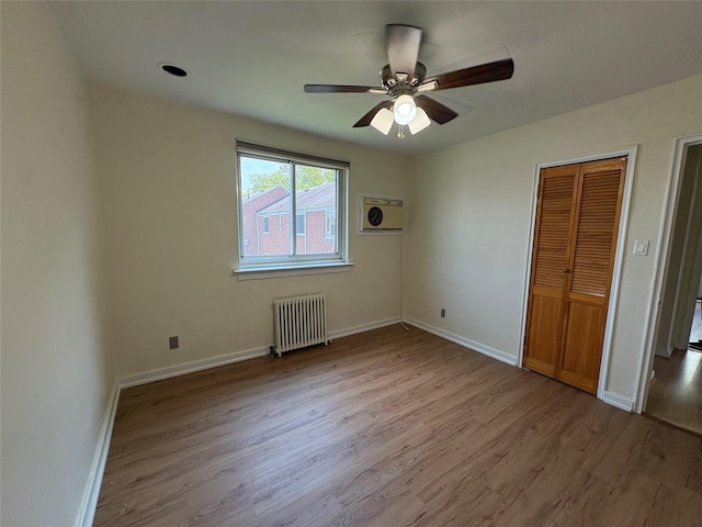 255-31 75th Ave Fl 2Nd, Glen Oaks, NY 11004 - unfurnished bedroom with radiator heating unit, wood finished floors, a ceiling fan, and a wall unit AC