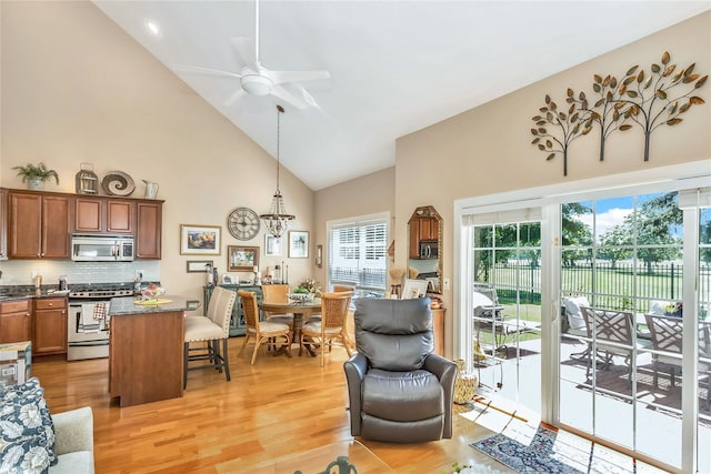 122 Maya Cir, Central Islip, NY 11722 - living area with high vaulted ceiling, light wood finished floors, a ceiling fan, and a chandelier