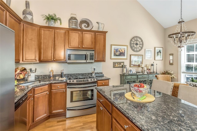 122 Maya Cir, Central Islip, NY 11722 - kitchen featuring stainless steel appliances, a chandelier, backsplash, brown cabinets, and high vaulted ceiling