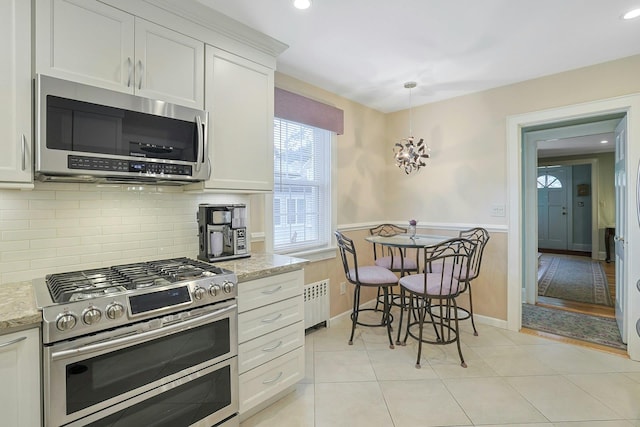 41 Cowdrey St, Yonkers, NY 10701 - kitchen featuring stainless steel appliances, radiator heating unit, backsplash, light stone countertops, and white cabinets