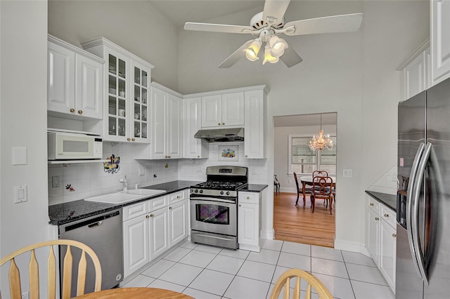 17 Singworth St, Oyster Bay, NY 11771 - kitchen with appliances with stainless steel finishes, a high ceiling, under cabinet range hood, light tile patterned floors, and white cabinets