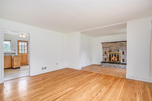 33 Grandview Ave, Pawling, NY 12564 - unfurnished living room with light wood-style flooring, a stone fireplace, and a ceiling fan