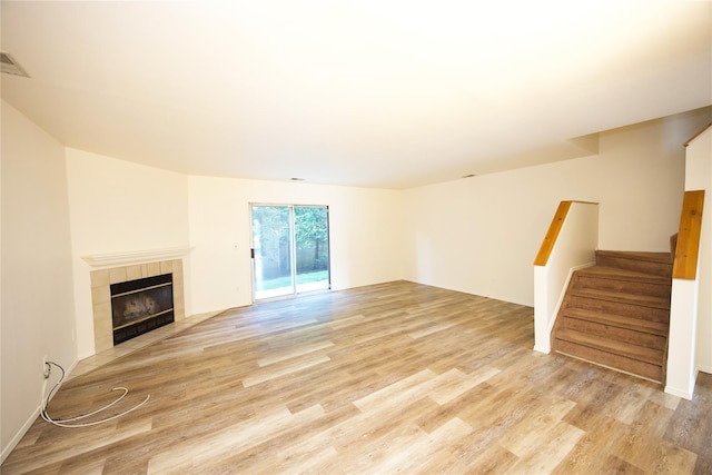 78 Stratford Grn, Farmingdale, NY 11735 - unfurnished living room with light wood-style floors, stairs, and a fireplace