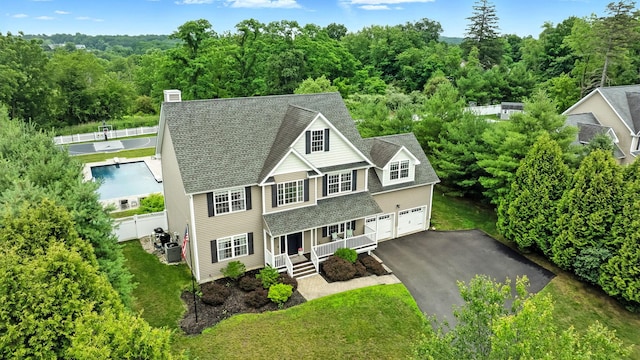 4 Brianna Ln, Yorktown Heights, NY 10598 - view of front of property featuring a porch, a garage, asphalt driveway, roof with shingles, and a view of trees