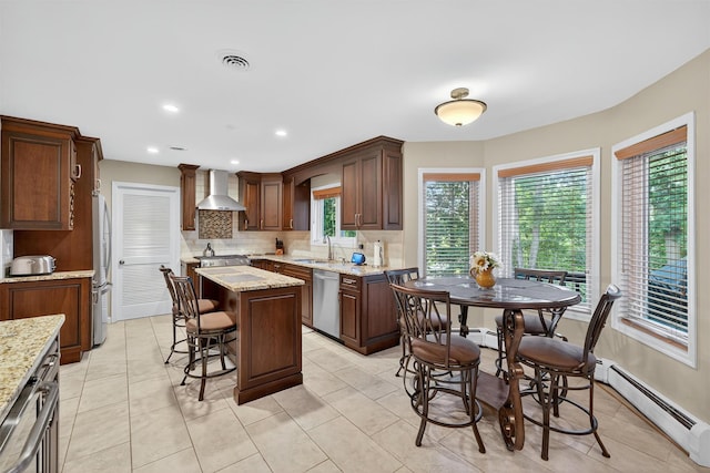 70 Walter Dr, Stony Point, NY 10980 - kitchen with appliances with stainless steel finishes, wall chimney exhaust hood, baseboard heating, tasteful backsplash, and a kitchen island