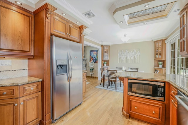 502 S 11th St, New Hyde Park, NY 11040 - kitchen with appliances with stainless steel finishes, ornamental molding, light wood-type flooring, brown cabinets, and backsplash