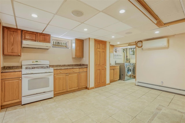 502 S 11th St, New Hyde Park, NY 11040 - kitchen featuring white gas range, under cabinet range hood, washing machine and dryer, a wall mounted AC, and a baseboard heating unit