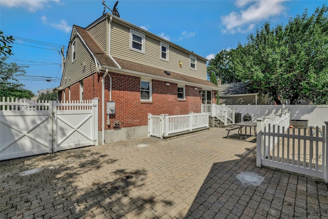 502 S 11th St, New Hyde Park, NY 11040 - back of house with a gate, brick siding, and a patio area