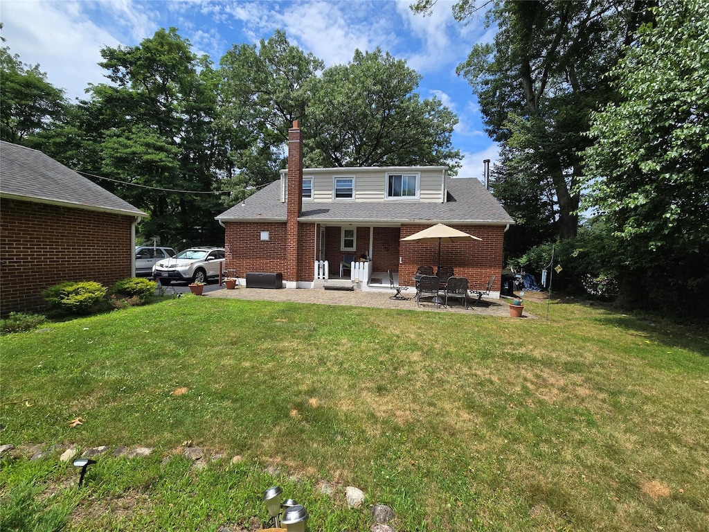 3 Birch St, Airmont, NY 10952 - back of house featuring a yard, brick siding, a chimney, and a patio
