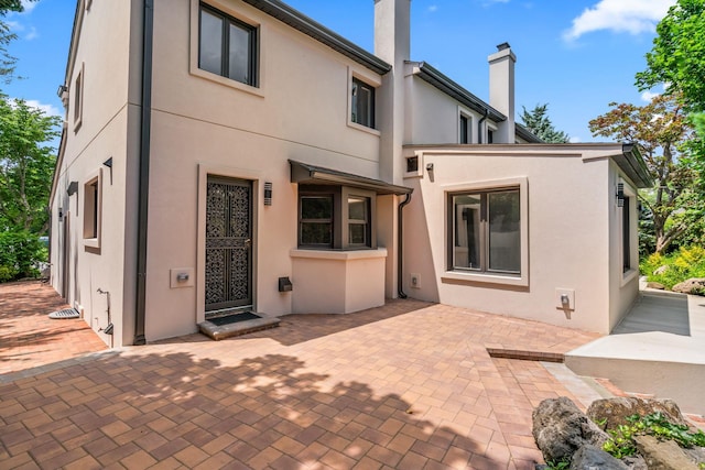 12 Foxhurst Ct, Manhasset Hills, NY 11040 - rear view of house with stucco siding, a chimney, and a patio area