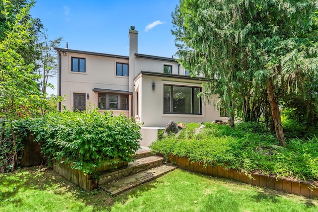 12 Foxhurst Ct, Manhasset Hills, NY 11040 - rear view of property with stucco siding, a chimney, and a lawn
