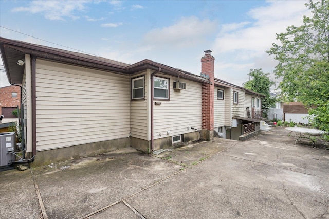 21 Silver St, West Babylon, NY 11704 - rear view of house with a patio area, a chimney, and a wall mounted air conditioner
