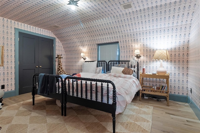 259 Westchester Ave, Pound Ridge, NY 10576 - bedroom with wallpapered walls, wood finished floors, lofted ceiling, and a closet