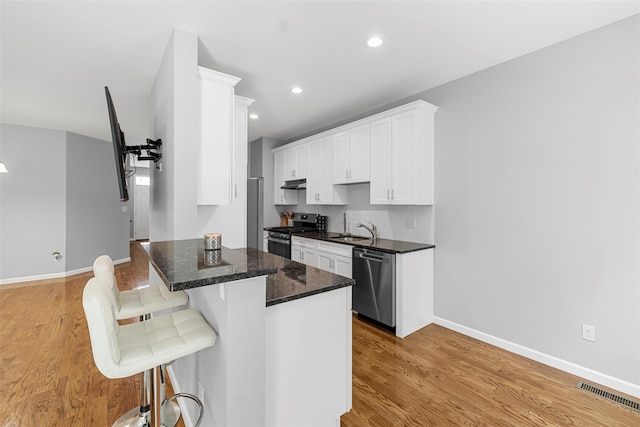 28 Pinto Rd W, Middletown, NY 10941 - kitchen with stainless steel appliances, a kitchen breakfast bar, light wood finished floors, under cabinet range hood, and white cabinets