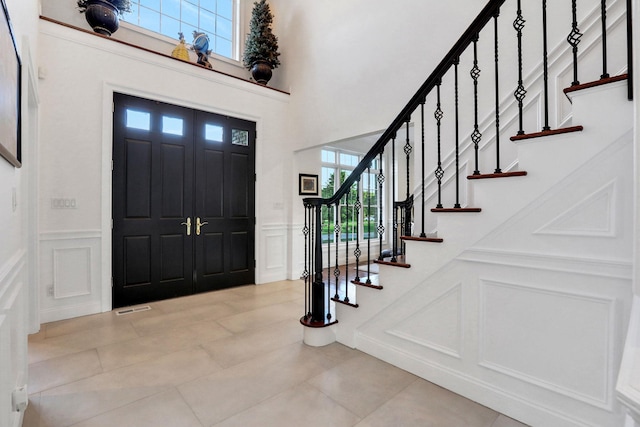 28 Viola Ct, Wappingers Falls, NY 12590 - foyer entrance with a decorative wall, light tile patterned flooring, stairway, a wainscoted wall, and a towering ceiling