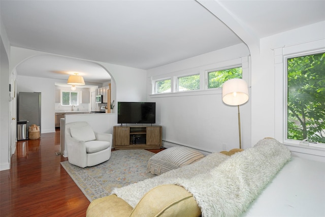 22 Tompkins Ave, Beacon, NY 12508 - living area with arched walkways, dark wood-style floors, and a baseboard heating unit