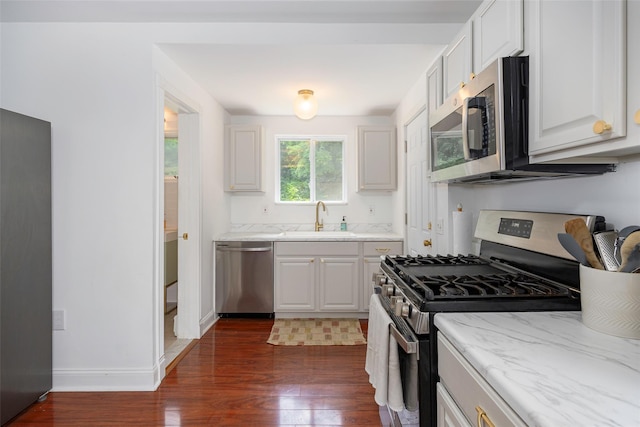 22 Tompkins Ave, Beacon, NY 12508 - kitchen featuring appliances with stainless steel finishes, dark wood-style flooring, light stone countertops, and white cabinetry