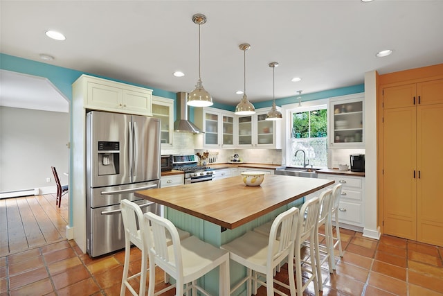 10 King St, Croton-On-Hudson, NY 10520 - kitchen with stainless steel appliances, butcher block countertops, wall chimney exhaust hood, tasteful backsplash, and a breakfast bar