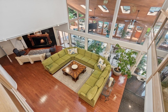 9 Swan Pl, Nissequogue, NY 11780 - living room with a towering ceiling, a lit fireplace, wood finished floors, and ceiling fan