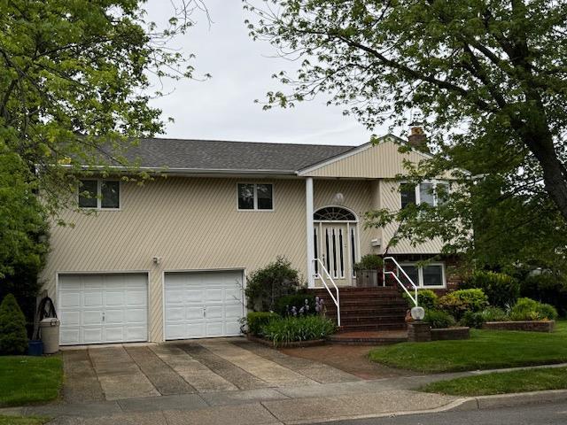 336 Thompson Ave, Oceanside, NY 11572 - split foyer home featuring a garage, a chimney, and concrete driveway
