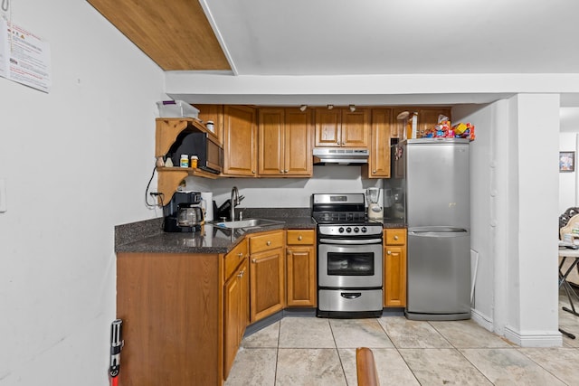 1160 E 89th St, Brooklyn, NY 11236 - kitchen with appliances with stainless steel finishes, under cabinet range hood, brown cabinetry, light tile patterned floors, and dark stone countertops