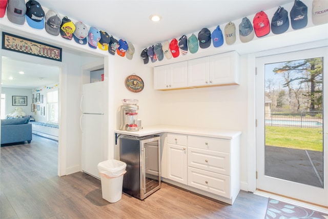 115 Highland Rd, Southampton, NY 11968 - kitchen with freestanding refrigerator, beverage cooler, light wood-type flooring, white cabinets, and recessed lighting