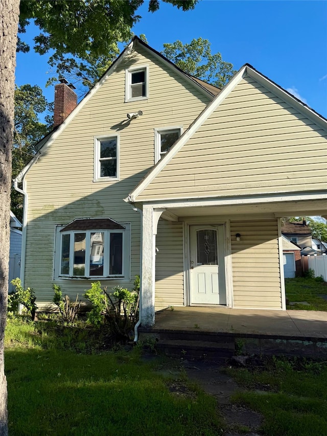 65 Mount Joy Ave, Freeport, NY 11520 - view of front of home with a chimney, a porch, and a front lawn