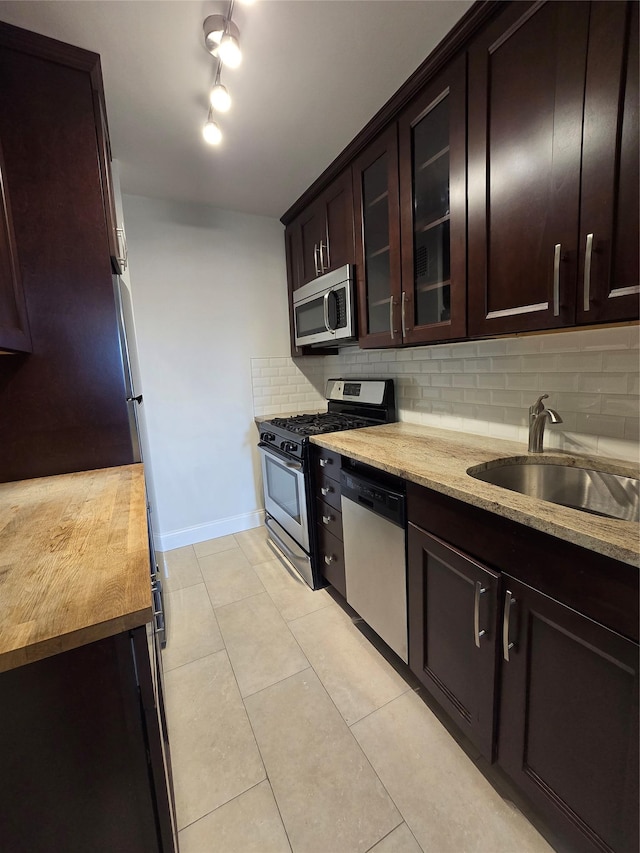 151-35 84th St Unit 1C, Howard Beach, NY 11414 - kitchen featuring stainless steel appliances, backsplash, light stone countertops, glass insert cabinets, and light tile patterned floors