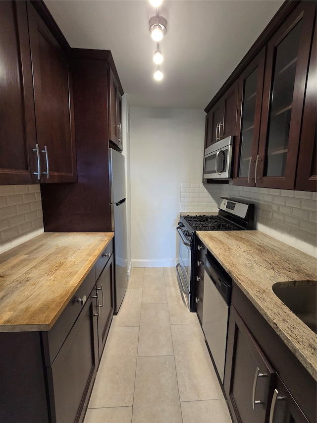 151-35 84th St Unit 1C, Howard Beach, NY 11414 - kitchen featuring stainless steel appliances, backsplash, dark brown cabinets, light stone counters, and glass insert cabinets