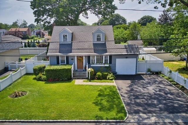 369 S 16th St, Lindenhurst, NY 11757 - cape cod-style house featuring asphalt driveway, an attached garage, and a shingled roof
