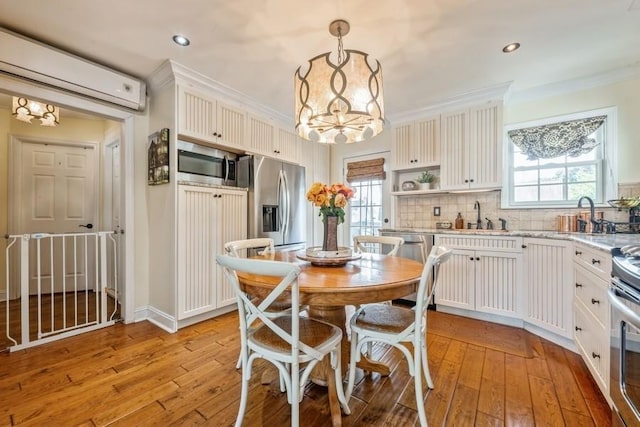 369 S 16th St, Lindenhurst, NY 11757 - kitchen featuring appliances with stainless steel finishes, an AC wall unit, a chandelier, decorative backsplash, and light wood-style floors
