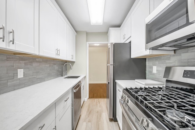 6 Birchwood Ct Unit 4G, Mineola, NY 11501 - kitchen with stainless steel appliances, backsplash, white cabinets, and light wood-type flooring