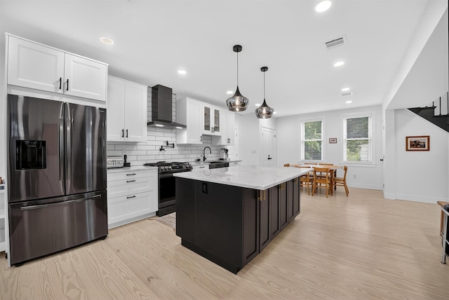 39 Frost Ln, Cornwall, NY 12518 - kitchen featuring appliances with stainless steel finishes, wall chimney exhaust hood, white cabinets, light wood finished floors, and tasteful backsplash