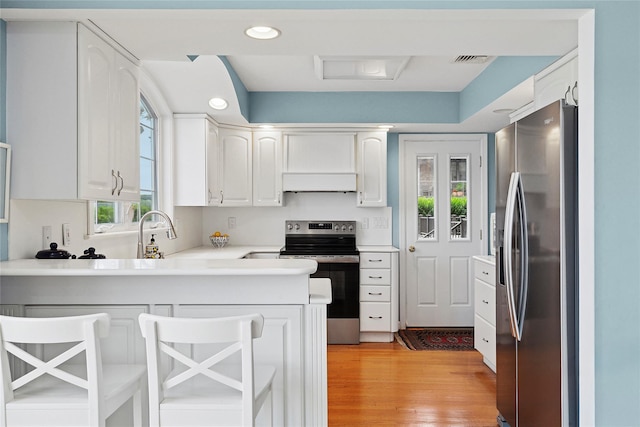 2055 Bay Shore Rd, Greenport, NY 11944 - kitchen with appliances with stainless steel finishes, a peninsula, white cabinets, extractor fan, and recessed lighting