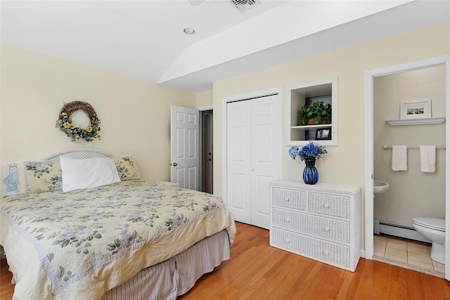 2055 Bay Shore Rd, Greenport, NY 11944 - bedroom featuring a baseboard heating unit, a closet, light wood finished floors, and connected bathroom