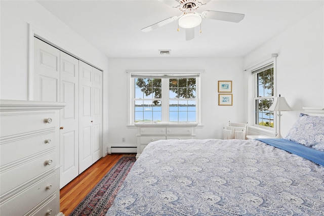 2055 Bay Shore Rd, Greenport, NY 11944 - bedroom featuring a baseboard radiator, wood finished floors, multiple windows, and a closet