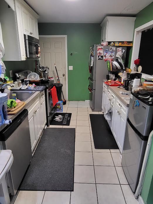 22 Prospect Ave, Brentwood, NY 11717 - kitchen with stainless steel appliances, light countertops, light tile patterned flooring, and white cabinets