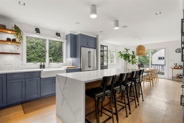 920 Protano Ln, Mamaroneck, NY 10543 - kitchen featuring freestanding refrigerator, decorative backsplash, light wood finished floors, and a breakfast bar