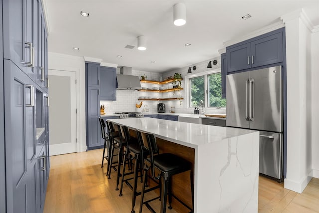 920 Protano Ln, Mamaroneck, NY 10543 - kitchen featuring freestanding refrigerator, a breakfast bar area, light stone counters, wall chimney range hood, and backsplash