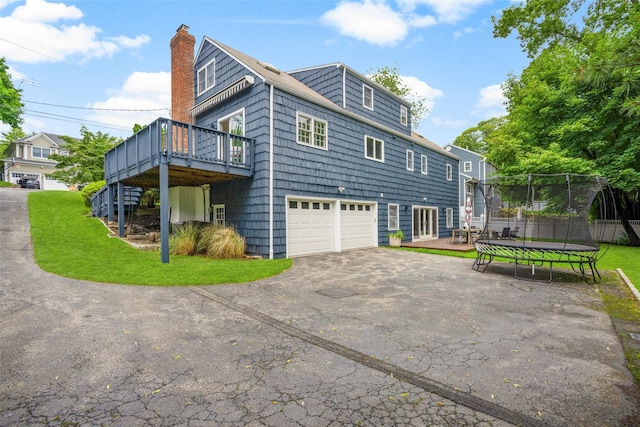 920 Protano Ln, Mamaroneck, NY 10543 - view of home's exterior featuring a trampoline, a deck, a chimney, asphalt driveway, and a garage