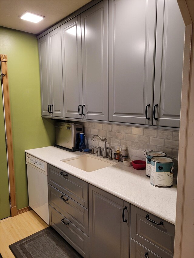 25 Herman Ave, North Babylon, NY 11703 - kitchen featuring white dishwasher, gray cabinets, light wood-type flooring, backsplash, and light countertops
