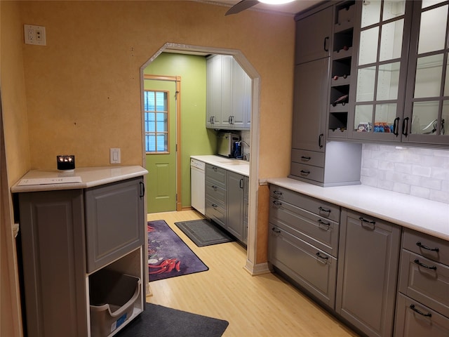 25 Herman Ave, North Babylon, NY 11703 - kitchen featuring light wood finished floors, gray cabinetry, decorative backsplash, arched walkways, and dishwasher