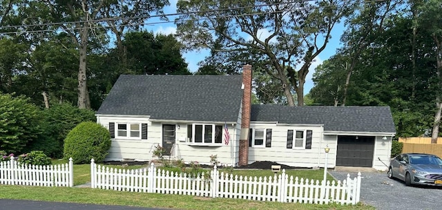 12 William St, Port Jefferson Station, NY 11776 - cape cod home with a chimney, an attached garage, a fenced front yard, driveway, and a shingled roof