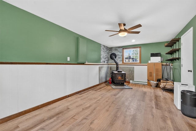 54 Graby Rd, Callicoon, NY 12723 - workout room featuring a wood stove, wood finished floors, a ceiling fan, and a baseboard radiator