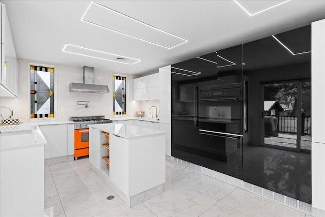 544 Oxford Rd, Cedarhurst, NY 11516 - kitchen with wall chimney exhaust hood, gas range, modern cabinets, white cabinetry, and a kitchen island