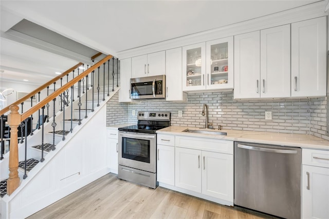 63 Old Farm Rd, Levittown, NY 11756 - kitchen with appliances with stainless steel finishes, tasteful backsplash, white cabinets, light wood-type flooring, and glass insert cabinets