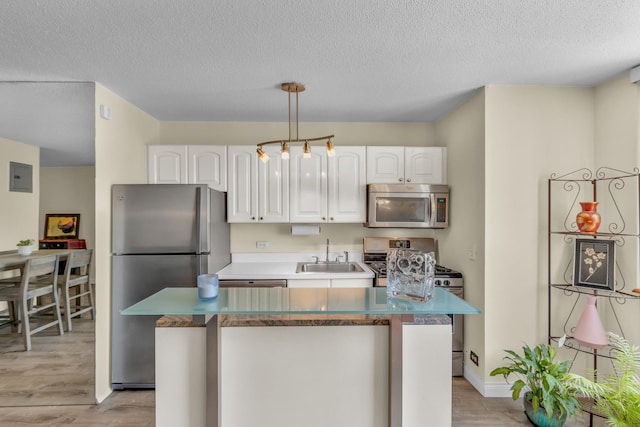 345 E 93rd St Unit 2E, New York Manhattan, NY 10128 - kitchen featuring appliances with stainless steel finishes, white cabinets, light wood-style flooring, a textured ceiling, and electric panel